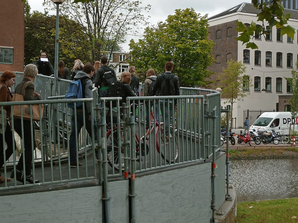 Students crossing a bridge on a university campus in Amsterdam